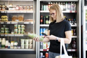 photo of woman choosing between green juice brands in supermarket
