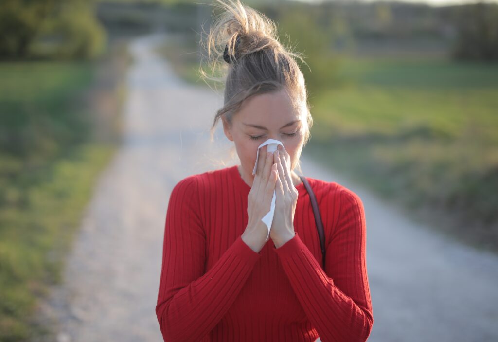 A female wearing red blouse who is having seasonal allergic reactions such as hay fever