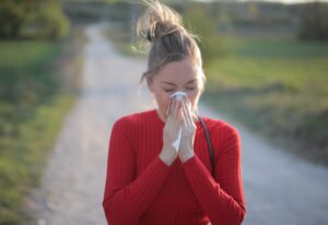 A female wearing red blouse who is having seasonal allergic reactions such as hay fever