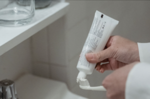 A toothpaste tube and toothbrush being used
