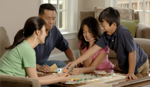 A photo of a family of four playing a board game at home